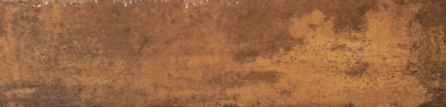 A close-up of the Galaxy 2x10 Porcelain Tile reveals a rusty, textured metal look in brown and orange tones with dark patches, capturing the unique industrial aesthetic of weathered luxury tiling.