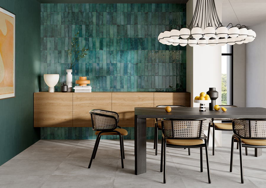 Modern dining room with a dark wood table, six chairs with cane backs, a geometric chandelier, and a green-tiled accent wall. Decorative items and fruit bowls are on the floating wooden sideboard.