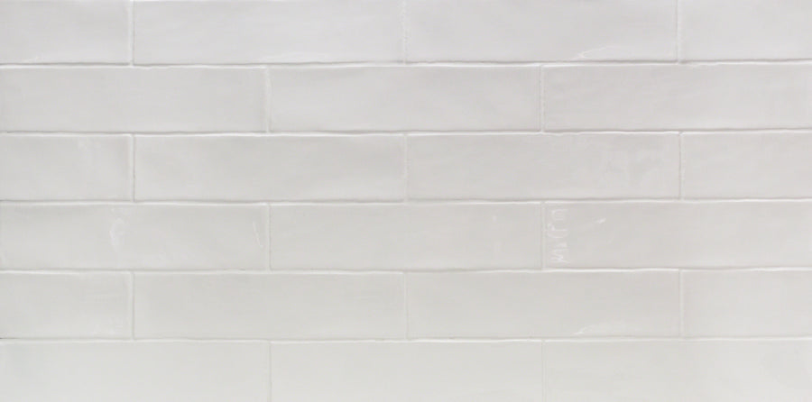 A close-up of Masia 3" x 12" Blanco subway tiles with a glossy finish and visible grout lines, arranged in a horizontal brick pattern—ideal for accent walls or kitchen backsplashes.
