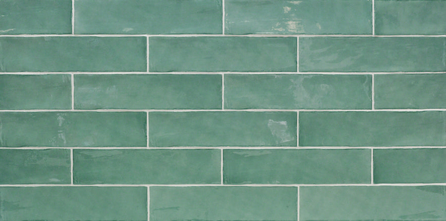 The Masia 3" x 12" Subway Tile in Jade features green rectangular tiles with a slightly glossy finish and subtle shade variation, arranged in a horizontal brick pattern with white grout—ideal for kitchen backsplashes or accent walls.