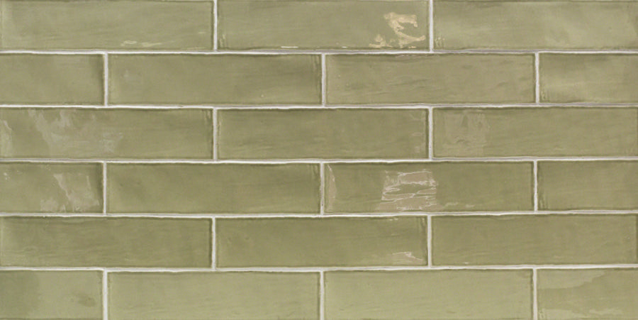 The Masia 3" x 12" Subway Tile in Olive features a glossy rectangular design, laid horizontally with white grout lines—ideal for accent walls or kitchen backsplashes.
