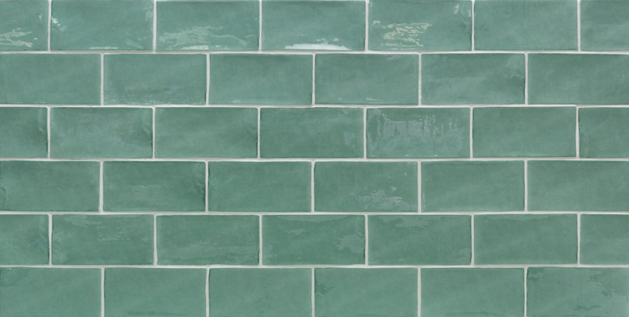 A close-up of a wall with Masia 3" x 6" Subway Tile in Jade, arranged in a brick pattern with white grout—an ideal, stylish choice for your kitchen backsplash.
