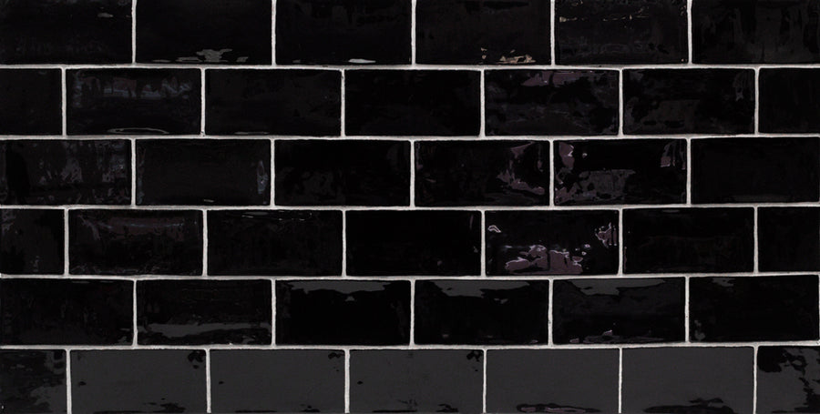 The Masia 3" x 6" Subway Tile in Nero, set in a horizontal brick pattern with visible grout lines, features a glossy finish that reflects light—ideal for adding sleek style to any kitchen backsplash.