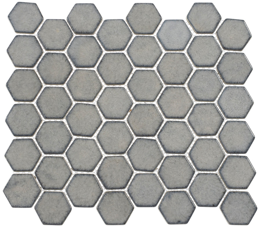 A close-up of the Greenwich 2" Hexagon Glass Mosaic Tile in Downtown Fervor, showcasing gray hexagonal tiles in a honeycomb pattern with thin white grout lines—ideal for a contemporary look.