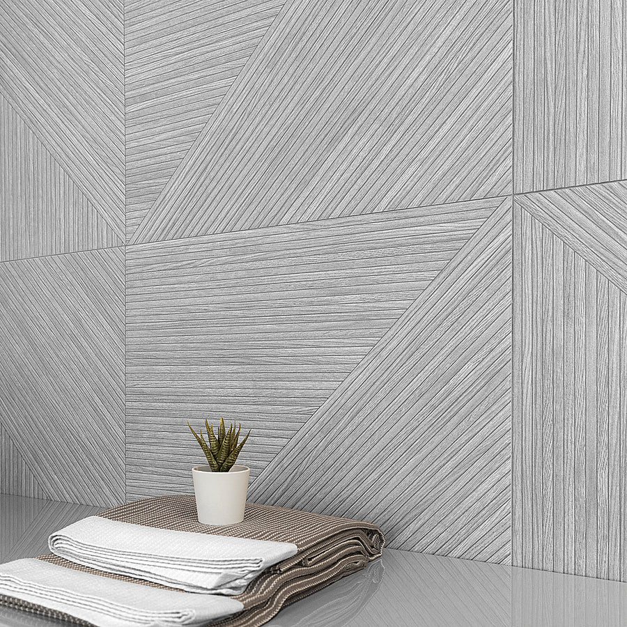 A small potted succulent sits on a glossy surface beside neatly folded towels, with a modern, geometric-patterned gray wall in the background.