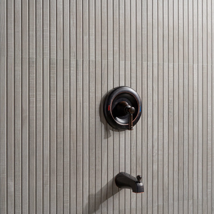 A modern shower faucet with a single-handle control and a tub spout installed on a light gray, vertically textured tile wall.