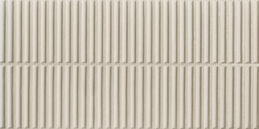 The Dunes 12x24 Porcelain Tile features a beige color, vertical ribbed texture, and matte finish with subtle shading. Arranged in a grid pattern, these tiles with raised grooves are perfect for feature walls or backsplashes.
