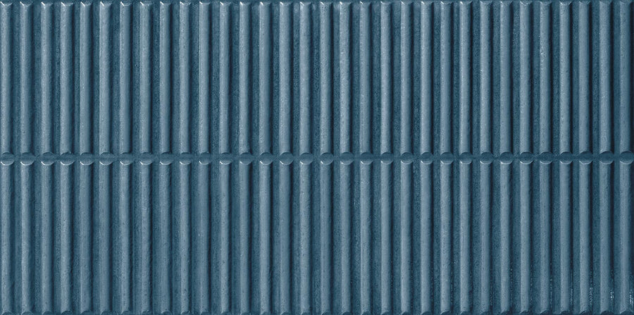 Close-up of Dunes 12x24 Porcelain Tile shows a textured blue surface with evenly spaced vertical ridges, divided horizontally—perfect for feature walls or backsplashes, offering a symmetrical, repeating pattern.
