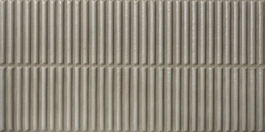 Close-up of Dunes 12x24 Porcelain Tile featuring vertical ridges and a horizontal groove in neutral grey, creating a repeating geometric pattern—perfect for modern backsplashes or wall designs.