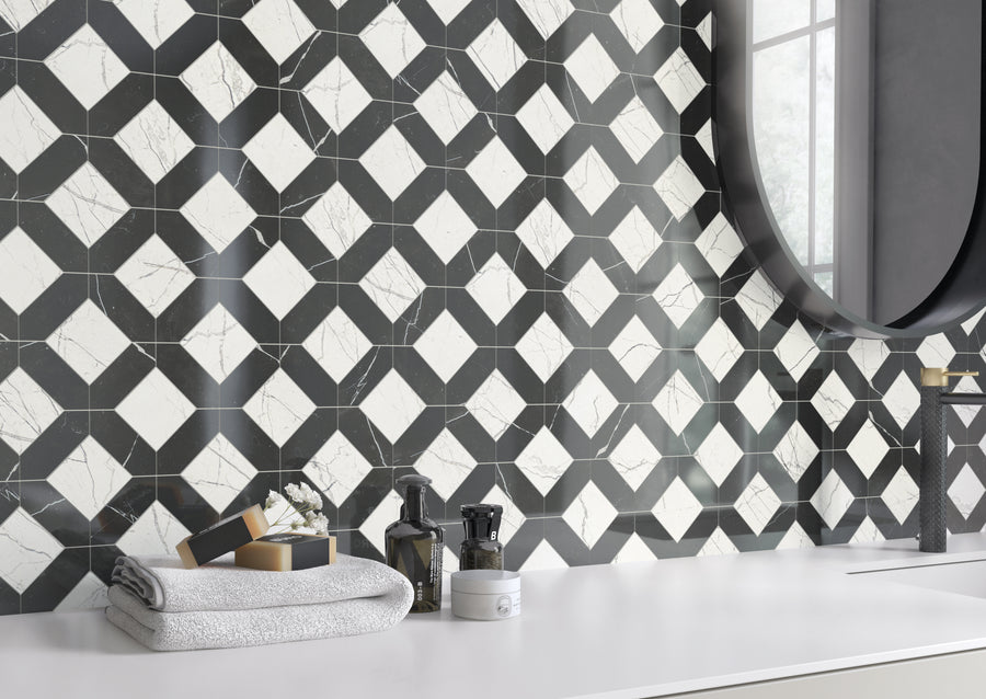 A modern bathroom countertop with folded towels, toiletries, and a vase. The wall features a black and white geometric tile pattern, and a large round mirror is partially visible next to a window.