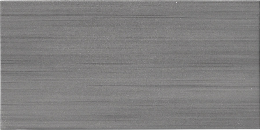 The Met 12x24 Porcelain Tile features a rectangular shape with a brushed, silvery-gray matte finish and horizontal streaks, offering a smooth, visually grained texture ideal for contemporary design trends.