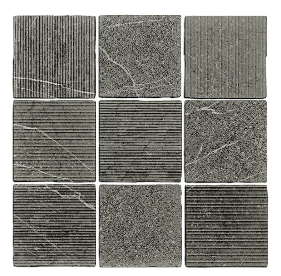 A 3x3 grid displays nine Gea Hand Carved 4.7" x 4.7" Ceramic Tiles in charcoal, each with unique textures and patterns like ridges, lines, and white veins, arranged on a white background.
