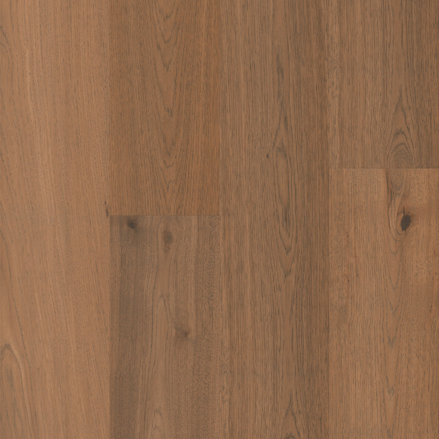 Close-up view of Gran Reserva 7 1/2" Hardwood in the Brambly color, featuring medium brown tones with visible grain patterns and occasional knots that highlight the natural wood texture and subtle color variations. The luxury flooring’s wide 7 1/2" planks provide a refined and elegant appearance.