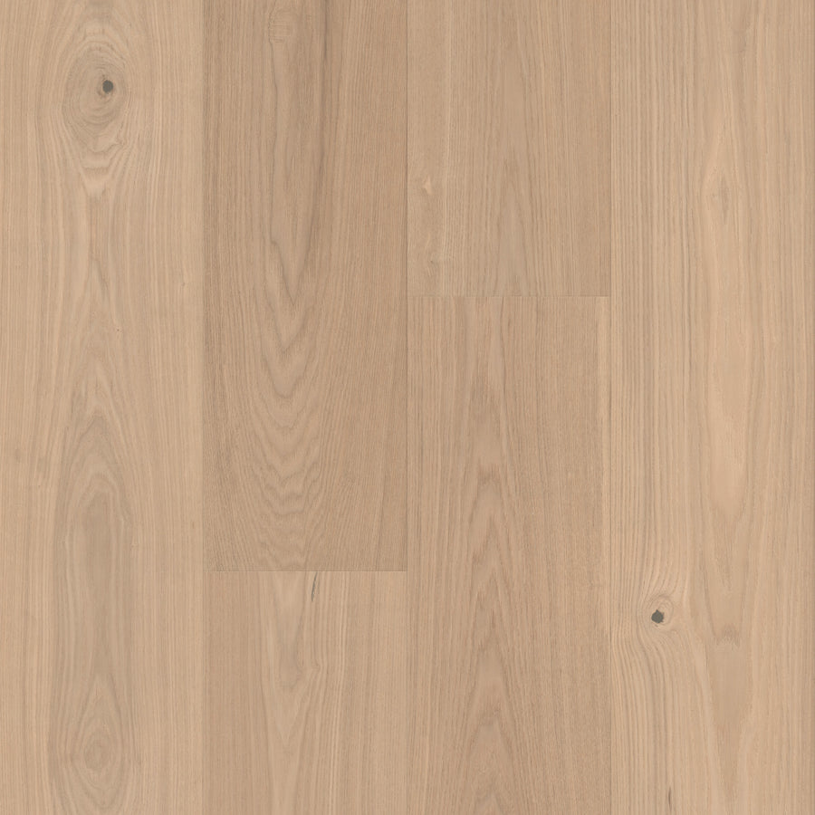 Gran Reserva 7 1/2" Hardwood in the Cava color features light wood floors with natural grain patterns and knots in a soft beige hue. The 7 1/2" wide planks are arranged parallel to each other, showcasing subtle variations in color and texture throughout the luxury flooring surface.