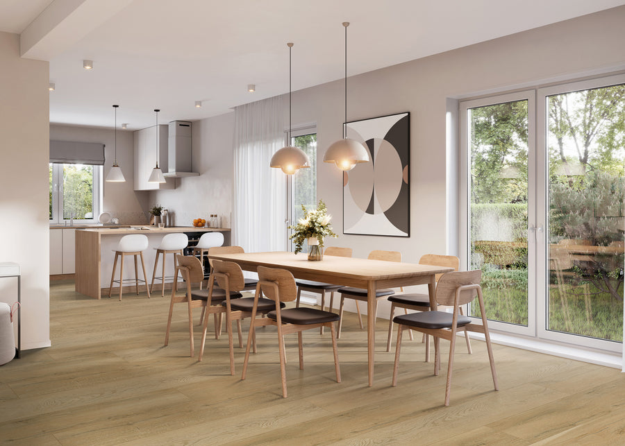 A modern dining and kitchen area with wooden floors, a large wooden dining table with eight chairs, pendant lights above, large windows, and a kitchen island with stools in the background.
