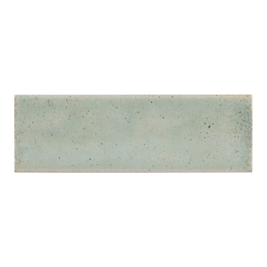 The Hanoi 2.5" x 8" Ceramic Subway Tile in Celadon features a hand-finished rectangular design with subtle speckles and a slightly textured surface.