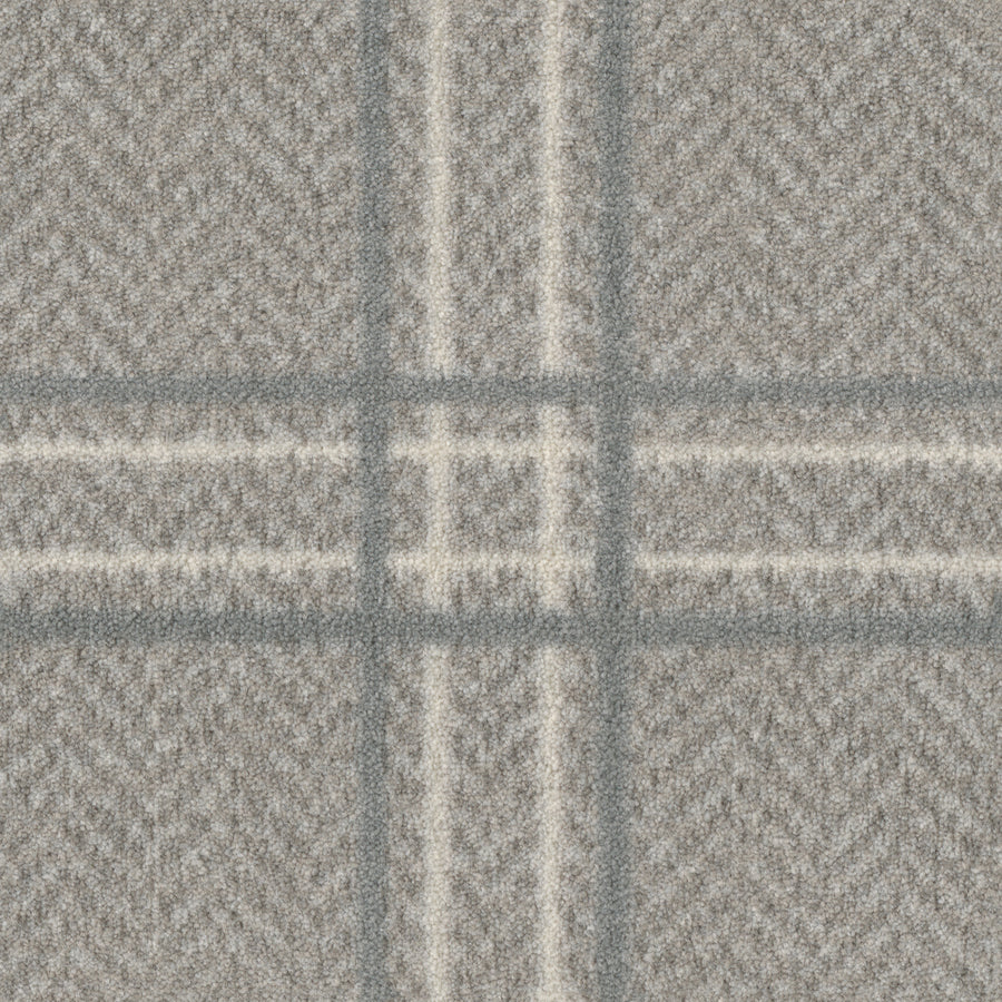 A close-up of Herrington On Trend Carpet in Quartz shows its textured grey herringbone fabric with intersecting plaid lines, perfect for contemporary spaces and high-traffic areas.