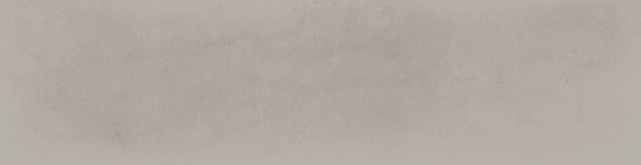 The Harmony 2.5x10 Porcelain Tile features a light beige, slightly textured surface with subtle grayish smudges and soft, uneven shading, evoking the look of handmade tile with a faintly dusty or chalky paper finish.