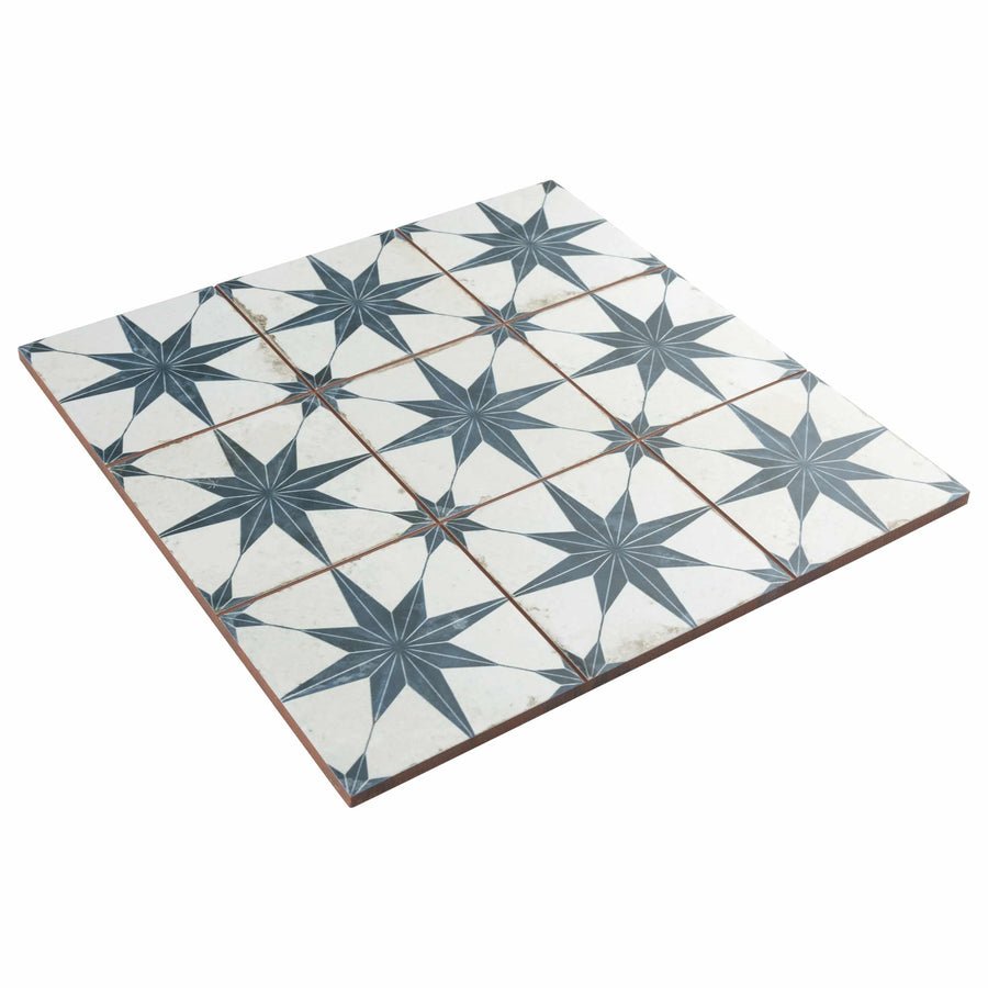A square arrangement of decorative ceramic tiles featuring a repeating pattern of dark blue eight-pointed stars on a white background with subtle speckles.