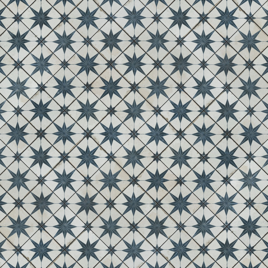 Geometric pattern of repeating dark blue star shapes with eight points, set against a white background with faint grey lines forming diamond shapes between the stars.