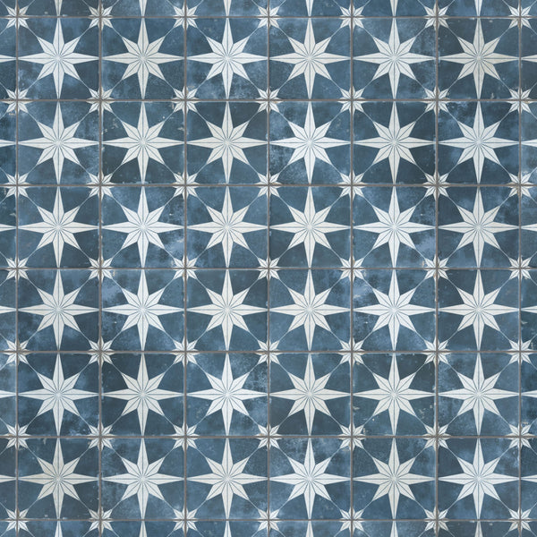 A patterned tile surface featuring repeating white eight-pointed stars on a blue background, with each star centered in a square, creating a geometric, symmetrical design.