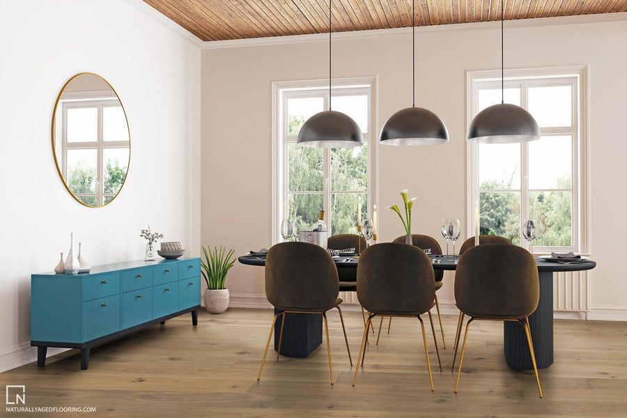 Modern dining room with a black table, six brown chairs, three pendant lights, and a blue sideboard under a round mirror. Large windows let in natural light, showing greenery outside.