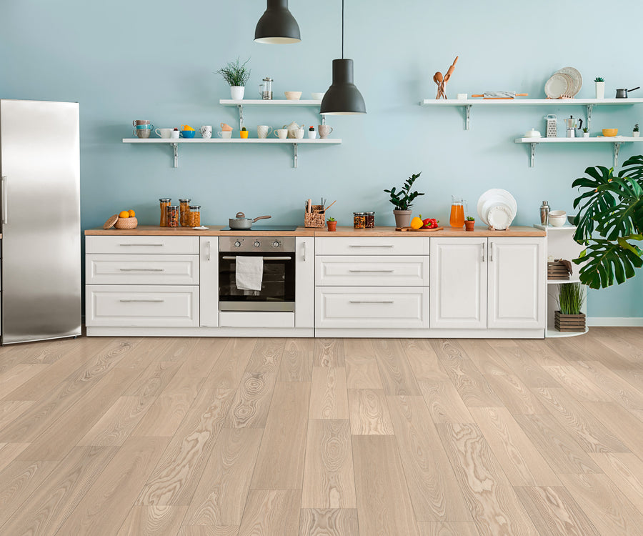 Modern kitchen with white cabinets, stainless steel appliances, open shelves displaying dishes, potted plants, and wooden countertops. The Huntington European Oak 7 1/2″ Hardwood floor, finished with a subtle reactive stain, along with a pale blue wall, creates a bright, airy atmosphere.