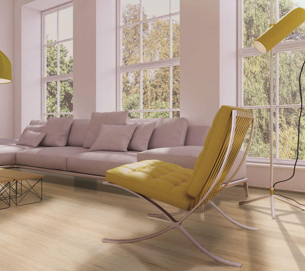 A modern living room with large windows, a light gray sectional sofa, a yellow lounge chair, a matching floor lamp, and a wooden coffee table. Daylight fills the space, highlighting the minimalist decor.