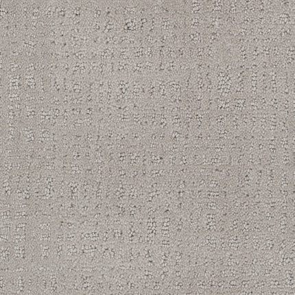 Close-up of the Homage Berber Carpet in Hypotnic, showcasing a light grey hue with a subtle, irregular grid pattern of raised threads and speckles. Its soft yet durable surface makes it perfect for comfortable, stylish high-traffic areas.
