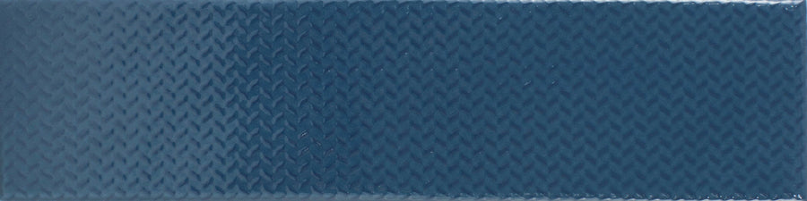 The Gradient 3" x 12" Ceramic Tile in Indigo Gloss features a textured surface with a subtle diamond pattern and a gentle color gradient that appears lighter toward the bottom.