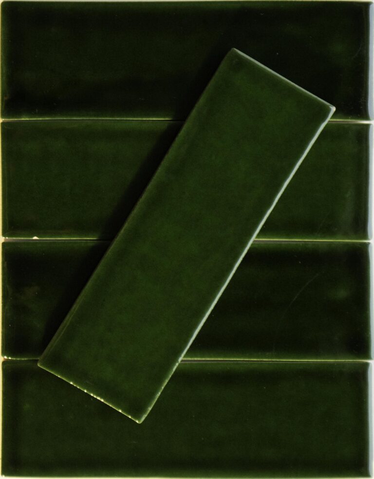 Five Noir Crackle 2.5x8 Ceramic Tiles in "I'm Feeling Pine," each with a glossy dark green finish, are arranged in rows—four horizontal and one diagonally across the center—for a bold layered look.