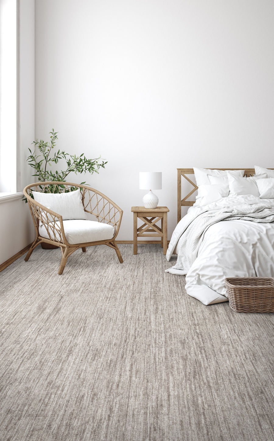 A bright, minimalist bedroom with a wicker chair, wooden bed, nightstand, white bedding, a small lamp, green plant, and a wicker basket on the light beige carpet. Sunlight streams in through a large window.