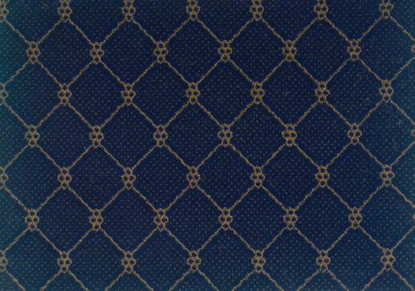 A close-up of Lake Boden Berber Carpet in Indigo showcases a dark blue textured surface with a repeating gold diamond crisscross pattern and small circular accents—ideal for stylish, durable modern home flooring.
