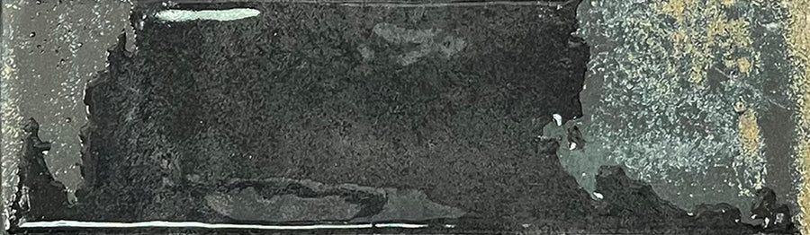 A rectangular Kinetic 2.5x9 Porcelain Subway Tile in the Fluid Force color features a dark, weathered metal appearance with a rough, uneven texture, lighter gray accents, and small spots of rust-like detailing that evoke the aged and distressed look often seen in artisanal pottery or well-worn porcelain tiles.