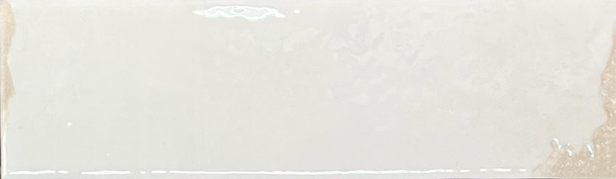 Introducing the Kinetic 2.5x9 Porcelain Subway Tile in Lively Latte: a rectangular tile featuring a glossy surface with a subtle, reflective glaze. Slightly uneven and artisanal in appearance, the left and right edges appear gently rough or unfinished—enhancing its handcrafted character and evoking the look of pottery-inspired design.