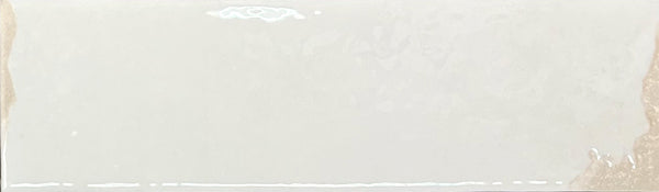Introducing the Kinetic 2.5x9 Porcelain Subway Tile in Lively Latte: a rectangular tile featuring a glossy surface with a subtle, reflective glaze. Slightly uneven and artisanal in appearance, the left and right edges appear gently rough or unfinished—enhancing its handcrafted character and evoking the look of pottery-inspired design.