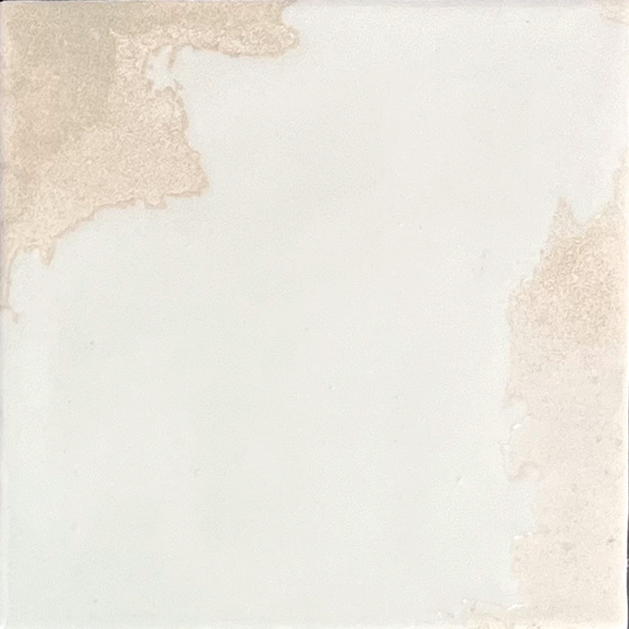 The Kinetic 4.5x4.5 Porcelain Tile in Lively Latte features a predominantly white surface accented by irregular beige patches and subtle textural variations, evoking the weathered charm of artisanal pottery.