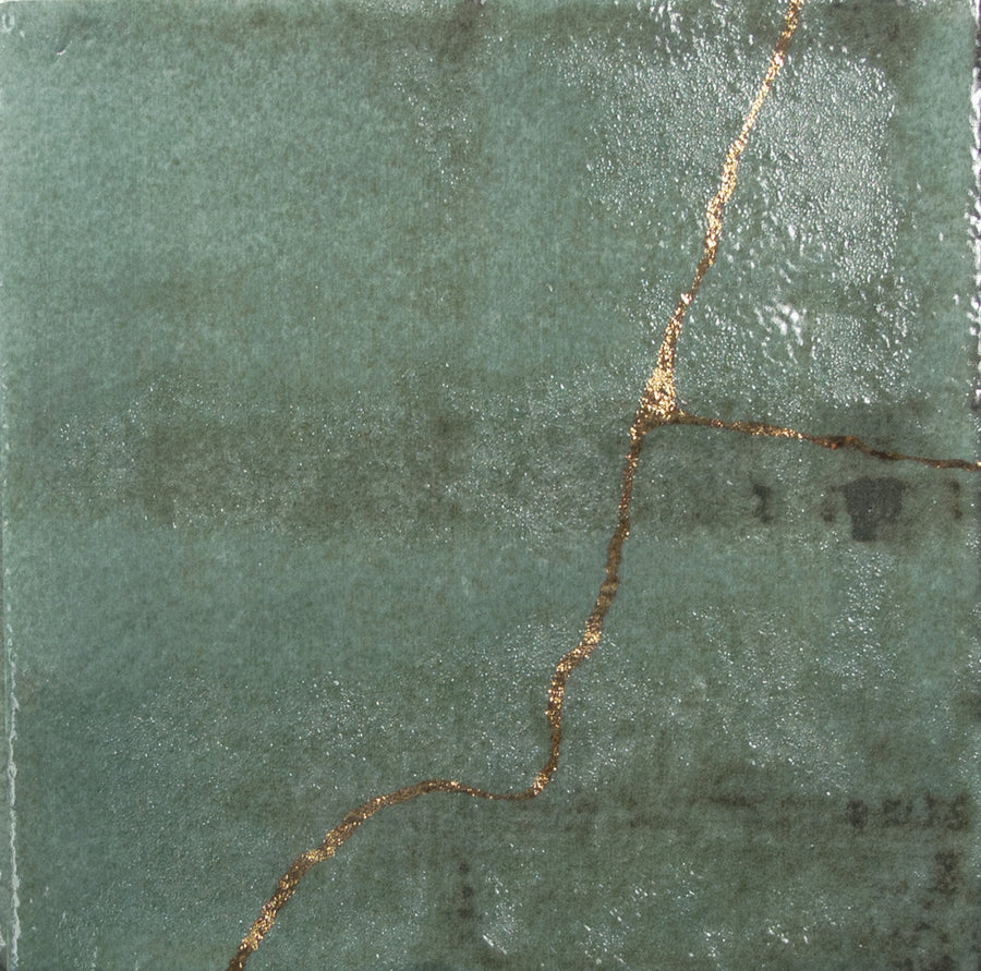The Kintsugi 5" x 5" Ceramic Tile in green showcases a gold-repaired crack, making it a striking accent piece or unique backsplash that celebrates the beauty of imperfection.