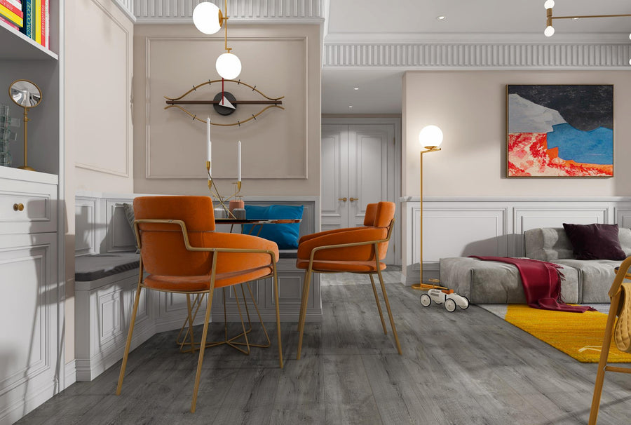 Modern living and dining area with orange velvet chairs around a small table, gray sofa, colorful abstract art on the wall, wooden floors, and a childrens toy car on a yellow rug. Warm lighting and cozy decor.