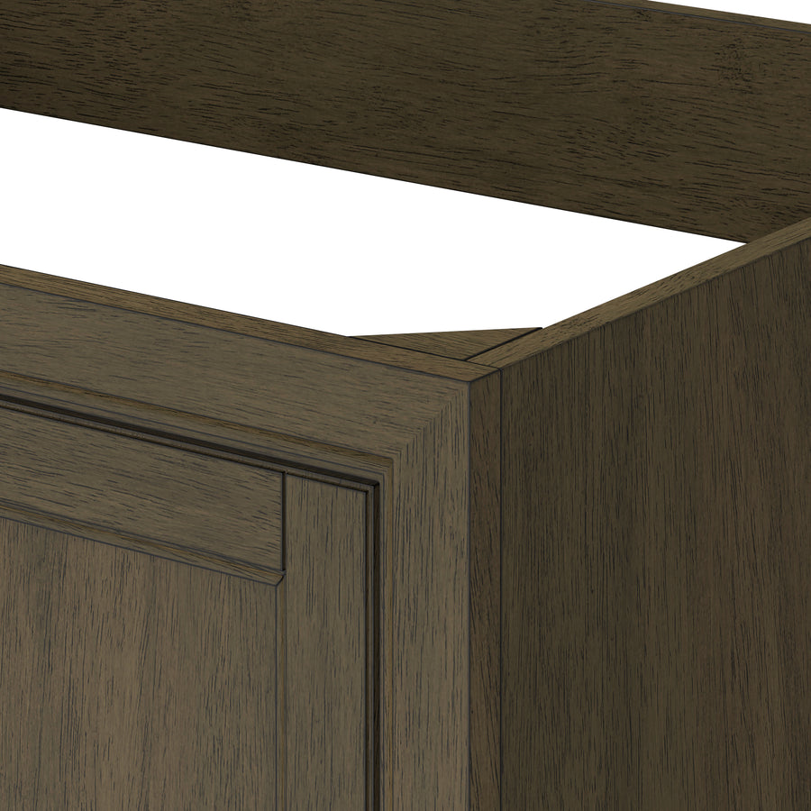 A close-up of a wooden cabinet corner with a dark brown finish, showing part of the side panel, front frame, and raised panel door. The top of the cabinet is open without a countertop.