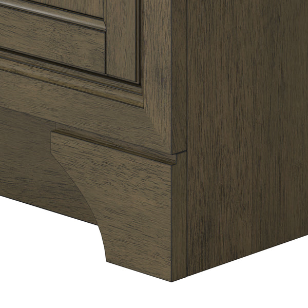Close-up of the bottom corner of a wooden cabinet or dresser, showing detailed wood grain and trim with a decorative cut-out design at the base.
