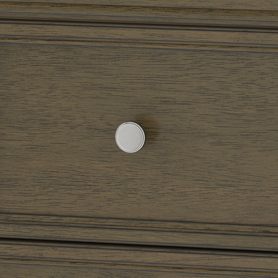 Close-up of a wooden drawer with a round, silver-colored knob in the center. The wood has a dark brown finish with visible grain texture.