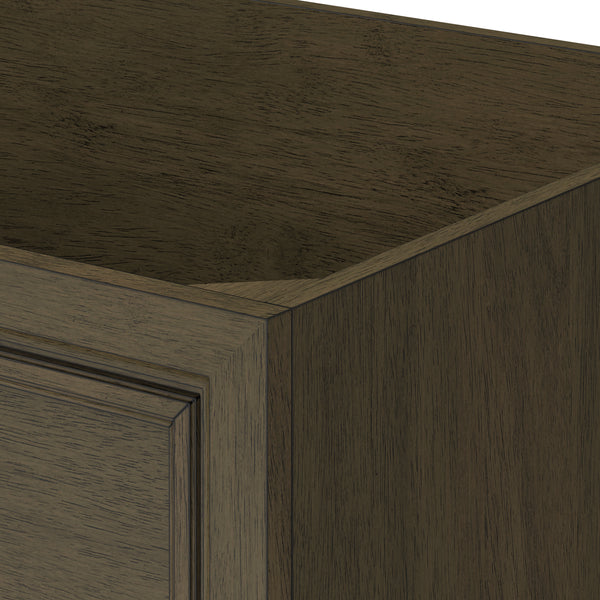 Close-up of the corner of a dark wood cabinet with a raised panel door, showing the grain and texture of the wood and the detailed edges of the frame.