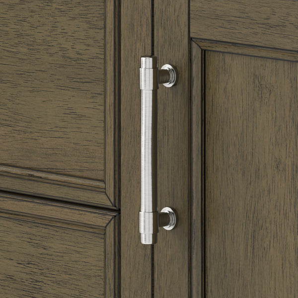 Silver metal cabinet handle with cylindrical shape mounted vertically on a wooden cabinet door with a brown, textured finish and panel detailing.