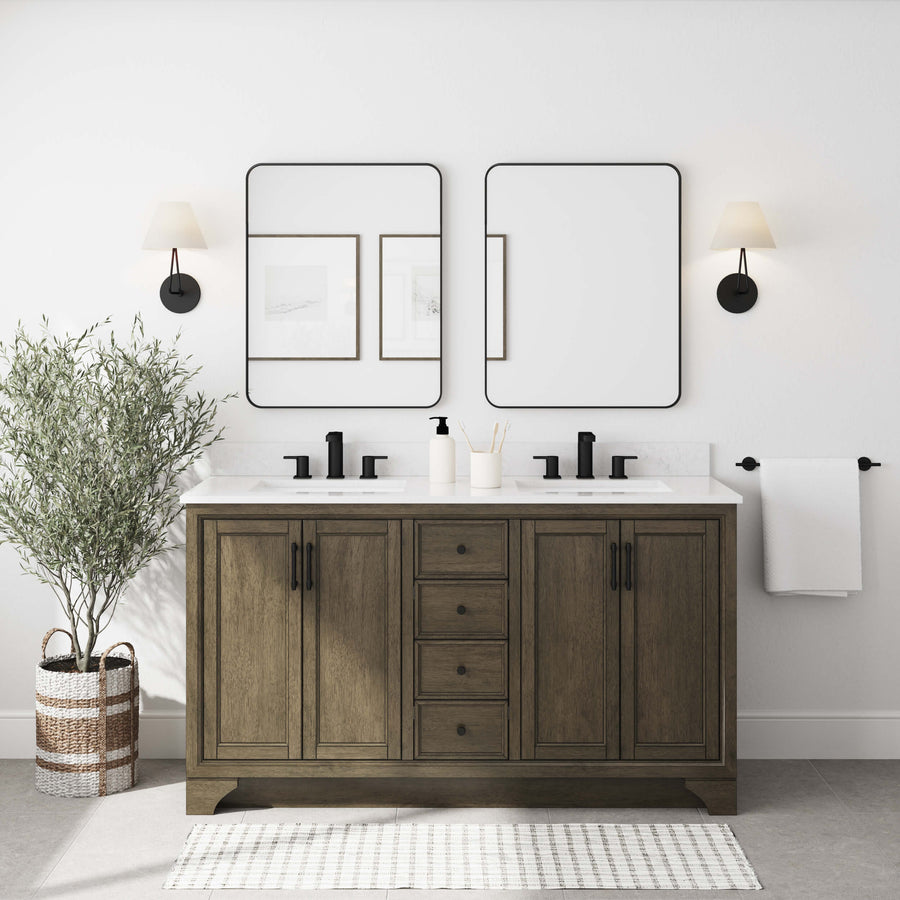 A modern bathroom features a double-sink wooden vanity with black fixtures, two rectangular mirrors, wall sconces, framed artwork, a potted plant, a towel bar with a white towel, and a striped rug on a light floor.