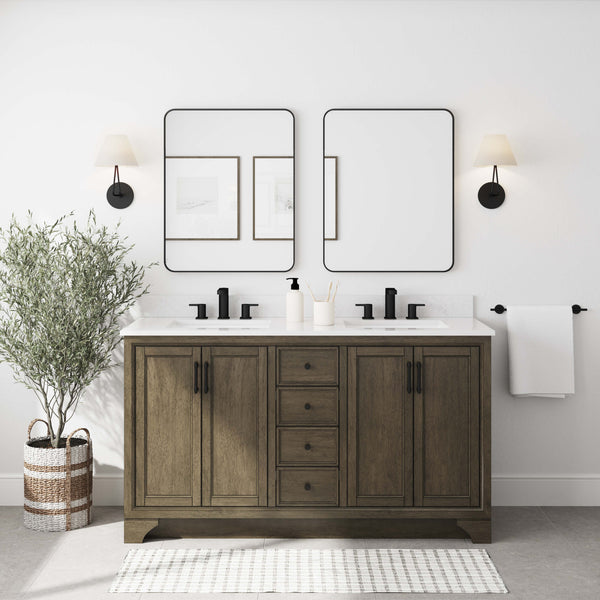 A modern bathroom features a double-sink wooden vanity with black fixtures, two rectangular mirrors, wall sconces, framed artwork, a potted plant, a towel bar with a white towel, and a striped rug on a light floor.