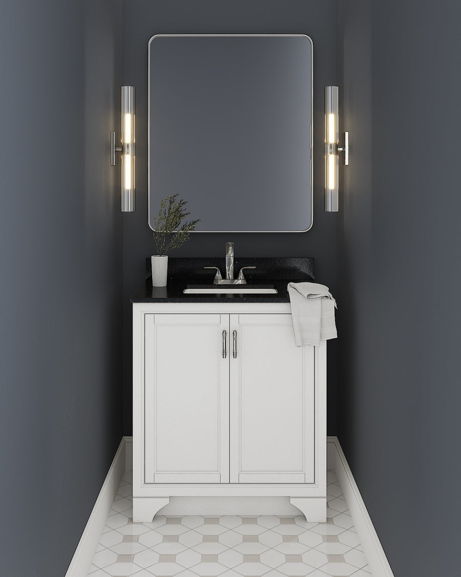 A modern bathroom with dark blue walls, a Lanagan 30" Vanity with double doors and black countertop, a square mirror, two wall sconces, a potted plant, a towel, and geometric-patterned floor tiles.