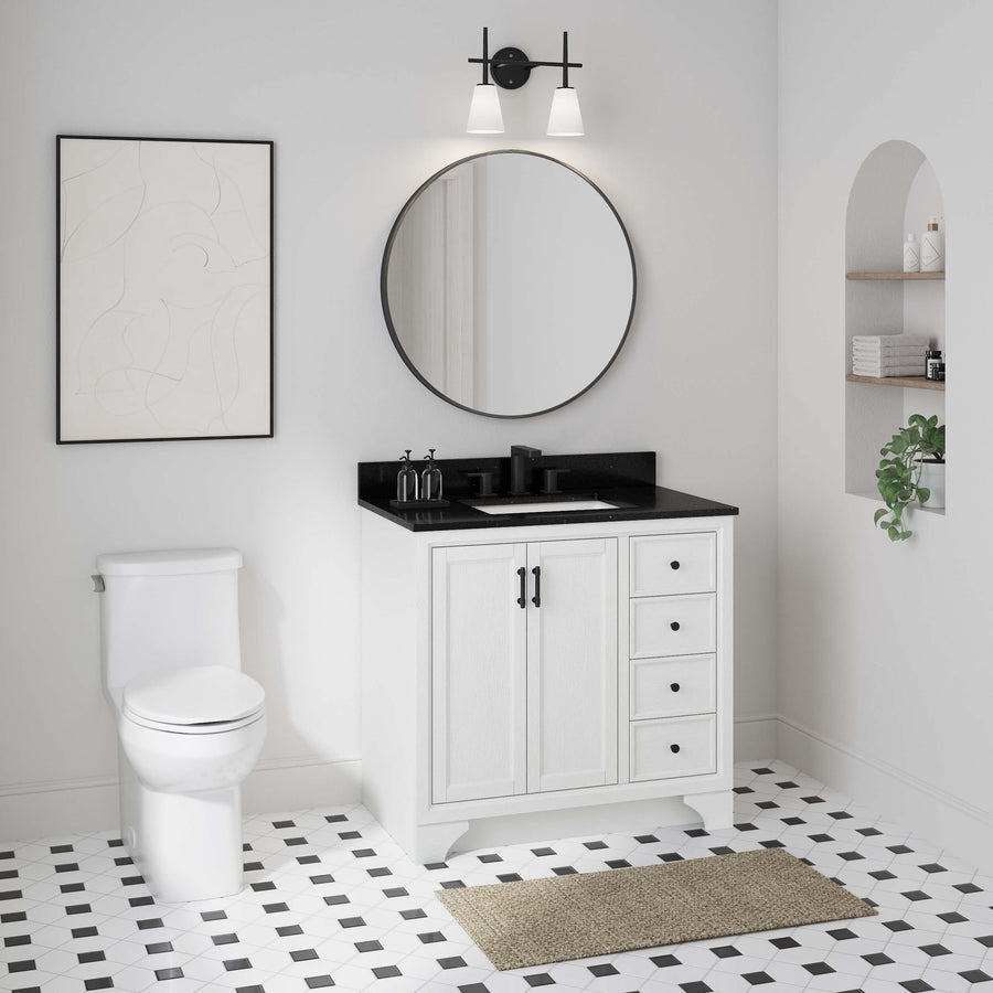 A modern bathroom with a black-and-white color scheme, featuring a round mirror above a white vanity, a toilet, wall art, built-in shelves with plants, and geometric floor tiles.