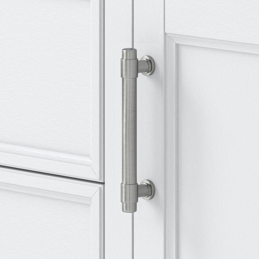 A close-up of a brushed metal cabinet handle attached to a white paneled cabinet door. The handle is cylindrical with simple, modern mounting hardware.