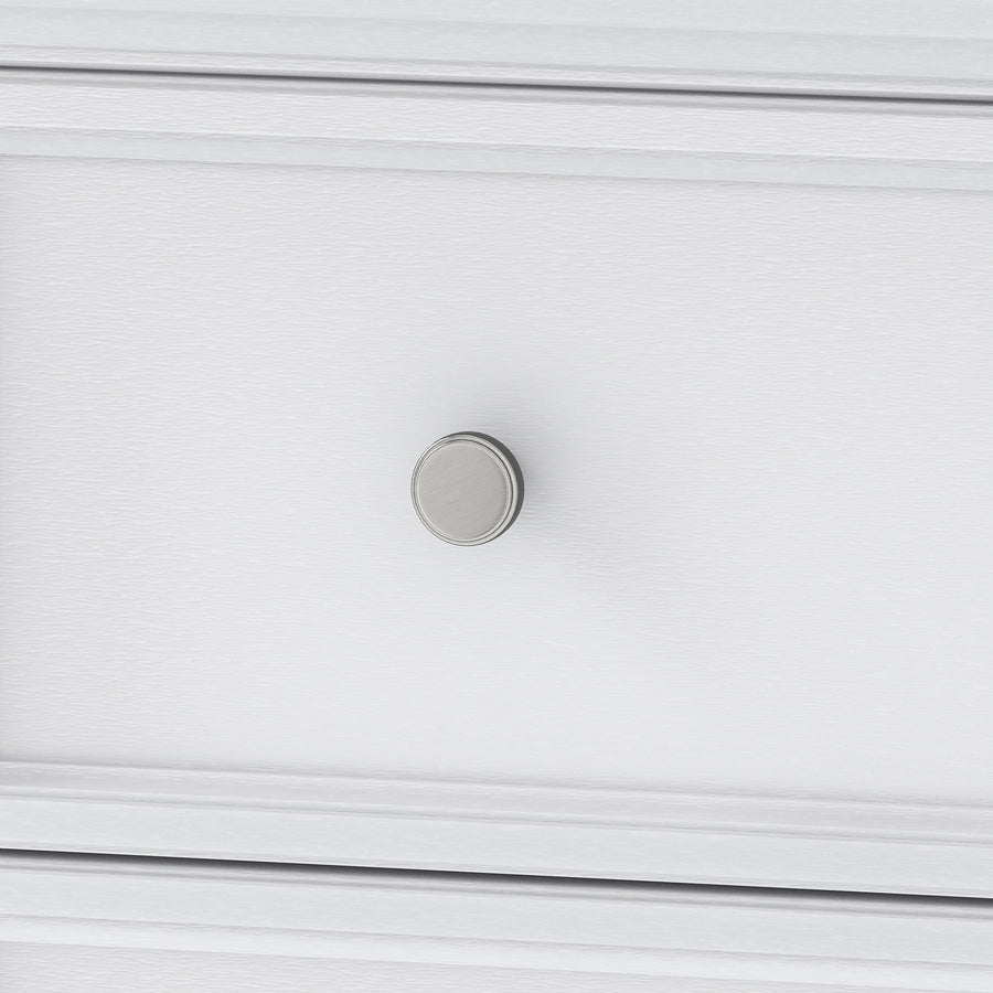 Close-up of a round, silver drawer knob on a white wooden drawer with a subtle textured finish. The image focuses on the knob and part of the drawer front.